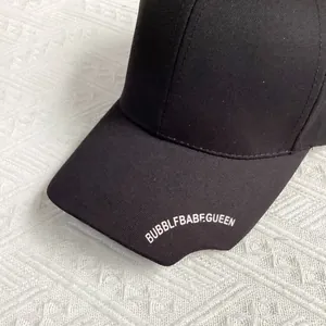 Close-up of black punk baseball cap with silver rivets and white embroidery detail