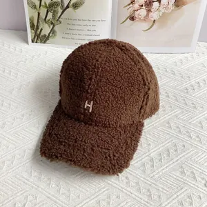 Close-up of fluffy coffee brown lamb wool baseball cap with embroidered letter H detail