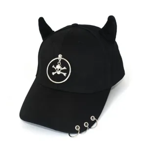 Dettaglio cappello punk nero con corna da demone e stemma in metallo con teschio