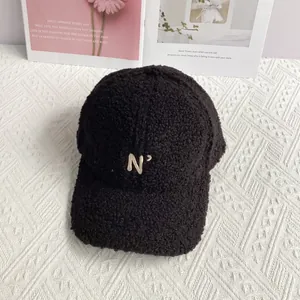 Detailed view of black fuzzy lamb wool baseball cap with gold N' letter embroidery