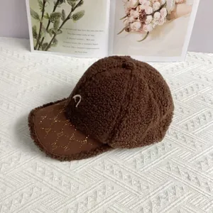 Detail einer braunen Teddy-Basecap mit weißem D-Buchstaben und glitzerndem Schirm