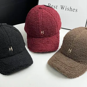 Detail view of lambswool baseball caps with gold H letter embroidery in three colors