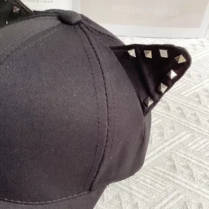 Detailed close-up of cat ear design with silver punk rivets on black canvas baseball cap