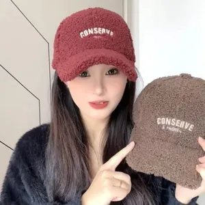 Close-up of red and brown fleece baseball caps featuring white letter embroidery