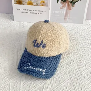 Detalle de gorra de béisbol de lana de cordero bicolor con bordado We en tejido crema suave