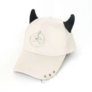 Dettaglio del cappello hip-hop beige con corna da diavolo e ciondolo a teschio silver