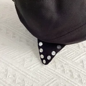 Close-up of black satin cat ear cap detail with silver metal punk rivets and neat stitching