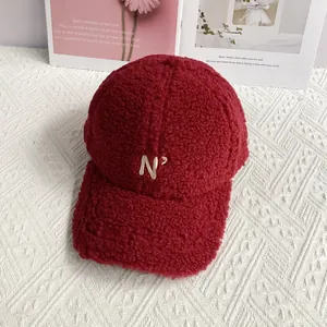 Detail of embroidered 'N' logo on wine red fleece baseball cap with soft texture