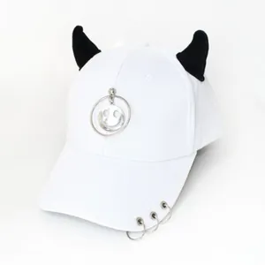 Dettaglio cappello punk bianco con corna da diavolo nere e pendente smiley in metallo argento