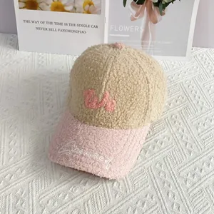 Detalle de gorra de béisbol beige y rosa con bordado W y textura suave de lana de cordero