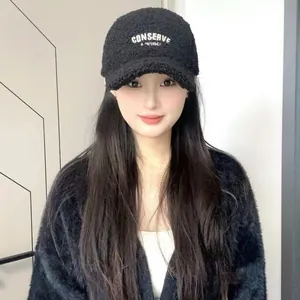 Detail of embroidered letters on warm black faux shearling baseball cap for winter