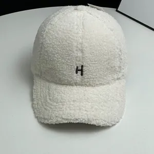 Close-up of white fleece baseball cap with black embroidered H letter and soft texture