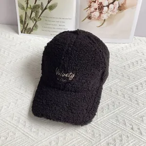 Close-up of black sherpa baseball cap with gold embroidery and woolly texture