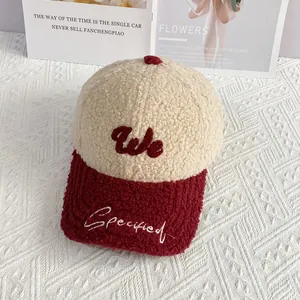 Detalle de gorra de béisbol de felpa con bordado 'We' y tonos cálidos crema y borgoña