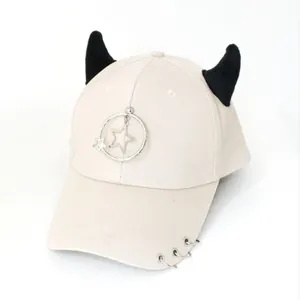 Dettaglio del cappellino punk crema con corna nere e ciondoli a stella con anelli metallici