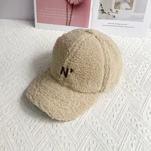 Detail of embroidered 'N' logo on cozy beige sherpa baseball cap for autumn and winter