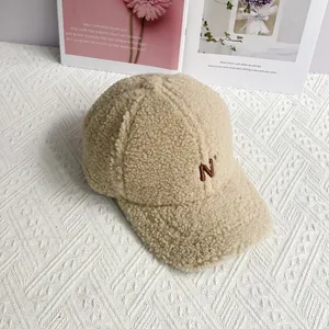 Detail of embroidered brown N letter on beige sherpa fleece baseball cap texture