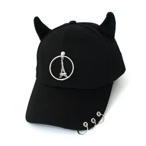 Dettaglio del cappello nero con corna di demone, anelli d'argento e ciondolo Torre Eiffel