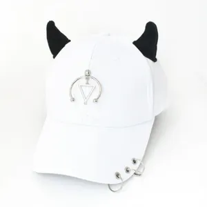 Dettaglio del cappellino bianco con corna da diavolo nere e anelli metallici in argento