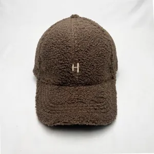 Close-up of fluffy teddy fleece baseball cap with white H letter embroidery in coffee brown