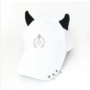 Dettaglio del cappello bianco con corna da diavolo nere e pendenti a forma di stella