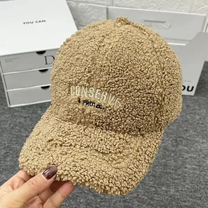 Detail of embroidered letters on thick khaki sherpa baseball cap for winter warmth