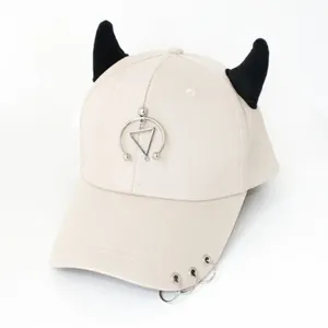 Dettaglio del cappellino hip-hop beige con corna nere e anelli metallici stile punk