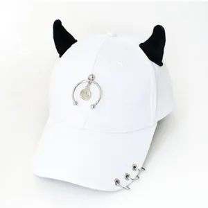 Dettaglio cappello bianco in cotone con corna di demone in peluche nero e anelli metallici