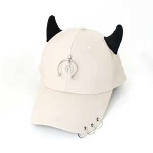Dettaglio del cappello punk beige con corna da diavolo nere e accenti in metallo argento