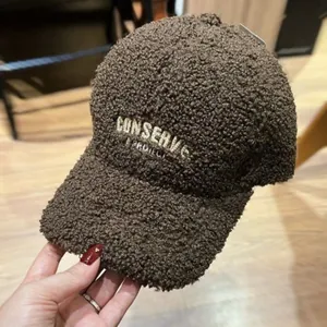 Close-up of thick brown faux lamb wool baseball cap with embroidered text and small studs
