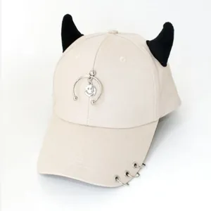 Dettaglio cappello beige con corna da diavolo nere e pendenti con anelli in metallo