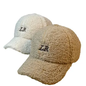Detailansicht der LR-Stickerei auf warmen Sherpa-Baseballkappen in Creme und Kamel