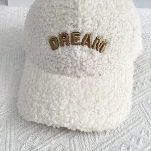 Detailaufnahme der DREAM 3D Stickerei auf weichem beigem Lammfell-Baseballcap