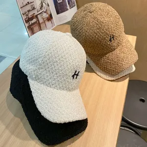 Detail van de H-borduring op zachte teddy fleece petten in neutrale kleuren