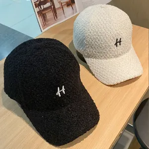 Fleece baseballpetten met H-borduurwerk in zwart en wit op een houten ondergrond