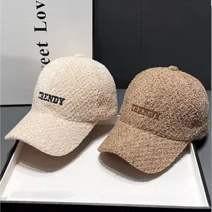 Detail view of plush teddy fleece baseball caps with TRENDY embroidery in beige and brown
