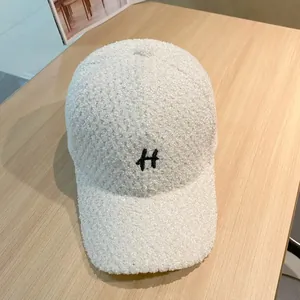 Close-up van de witte teddy fleece baseballpet met zwart geborduurd letter H detail