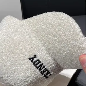 Close-up of white Sherpa fleece texture and black TRENDY letter embroidery on a cap