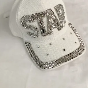 Close-up of STAR rhinestone embellishments on white faux fur baseball cap detail