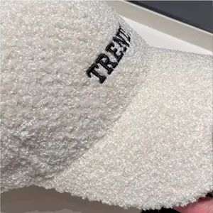 Macro detail of white teddy fleece baseball cap with black embroidered TRENDY text