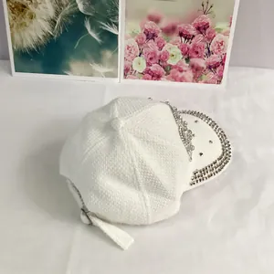 Detailed close-up of white knitted baseball cap with sparkling silver rhinestone trim