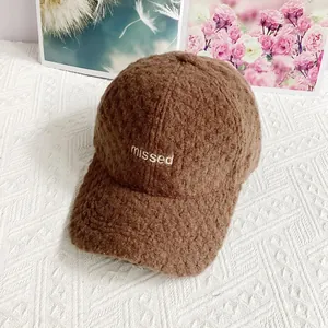 Nahaufnahme der braunen Teddy-Fleece-Kappe mit weißer missed-Stickerei auf weißem Stoff