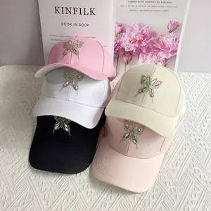 Detail showing five rhinestone butterfly baseball caps in pastel colors on a magazine