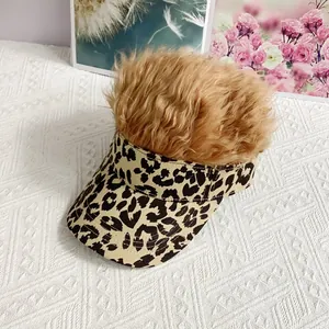 Detalle de la gorra con estampado de leopardo y peluca marrón sobre fondo blanco