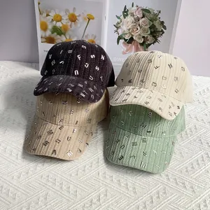 Dettaglio di cappellini da baseball in velluto con decorazioni a lettere metalliche
