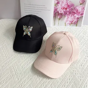 Detail view of rhinestone butterfly embroidery on black and pink baseball caps