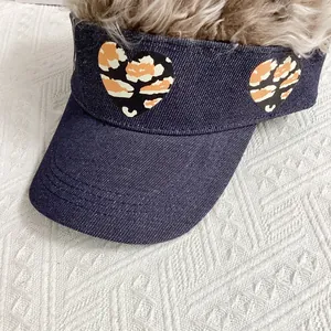 Detail of blue denim sun visor with heart shaped leopard print and sturdy brim