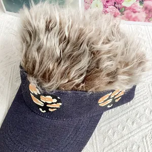 Macro detail of denim visor cap with blonde faux hair and tiger print heart patches