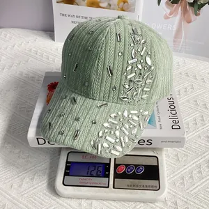 Detail of 126g green velvet baseball cap with shiny rhinestone embellishments on a scale