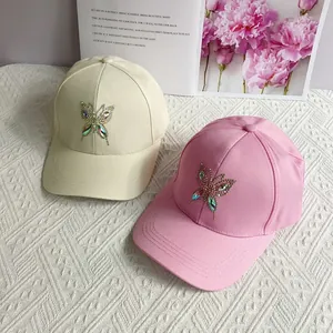 Close-up of rhinestone butterfly details on stylish beige and pink baseball caps
